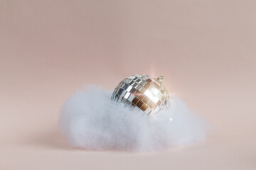 disco ball in an imitated cloud, pink background, empty space for text
