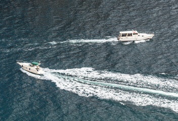 Top aerial view of two opposite speed and passenger boats with splashes on sea water