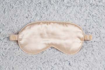 Golden sleep mask on a fluffy gray pillow. Comfortable sleep, soft eye mask for sleep.