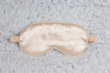 Selbstklebende Fototapeten Golden sleep mask on a fluffy gray pillow. Comfortable sleep, soft eye mask for sleep. © Настя ВольФ