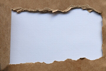 Brown paper flat lay with strip torn horizontally to reveal white copy space for advertising.