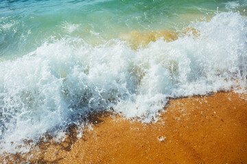 Sea foam on the sand beach with summer sunlight