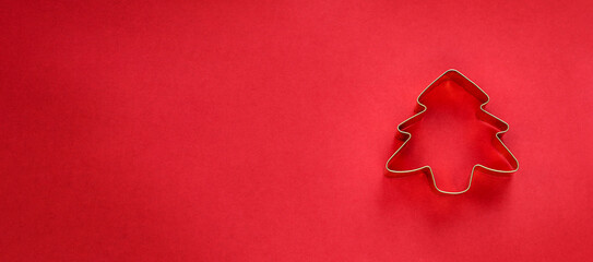 Christmas tree cookie cutter on red background banner. Minimalistic Christmas concept stock photo