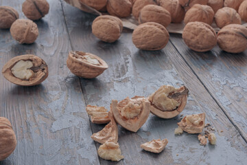 Close-up of a chopped walnut, on a blurry background a scattering of whole nuts in the shell and halves of an open walnut. Vintage style.