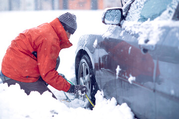 man prepares chains for tires on a cold day