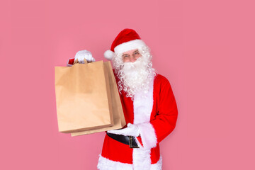 Santa Claus is smiling happily with shopping bags, with shopping and gifts on Black Friday and at Christmas sales. Big Christmas sale. Isolate on a pink background