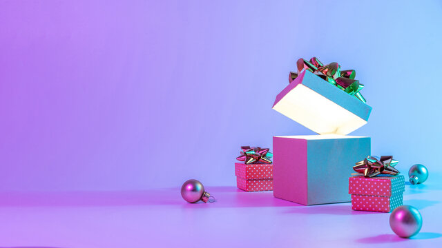 Neon xmas winter background. Open Christmas gift box with shine lights, minimal tree. Holiday decoration bauble ball on neon abstract gradient backdrop. Happy new year copy space. - Powered by Adobe