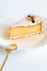 French flan on white plate with biscuit crumbs around, with almonds on top. Piece of cake on white bright background, traditional french  dessert