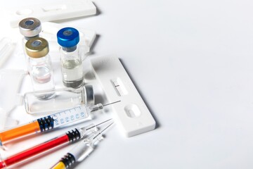 Positive SARS-CoV-2 Rapid Antigen Test and syringes. COVID-19 vaccine. Pandemic vaccination.