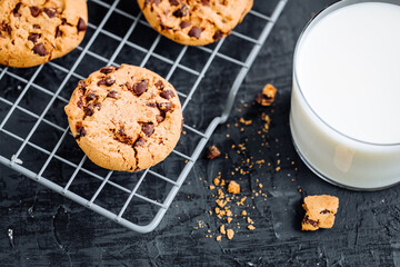Chocolate chip cookies with tea in background in a dark moody atmosphere 