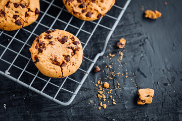 Chocolate chip cookies with tea in background in a dark moody atmosphere 