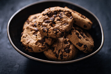 Chocolate chip cookies with tea in background in a dark moody atmosphere 