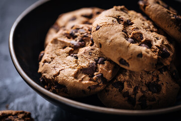 Chocolate chip cookies with tea in background in a dark moody atmosphere 