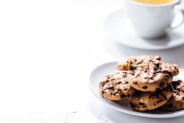 Cup of tea in white cup with chocolate chip cookies as a part of a scene, on a white background