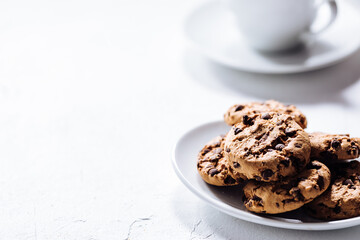 Cup of tea in white cup with chocolate chip cookies as a part of a scene, on a white background
