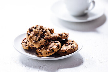 Cup of tea in white cup with chocolate chip cookies as a part of a scene, on a white background