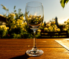 Un verre de vin vide posé sur une table de jardin en fin de journée d'été