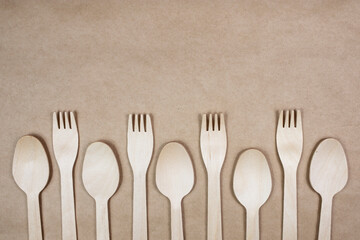 Disposable bamboo spoon and fork on a paper background with a natural ivy branch. Top view, place for text.