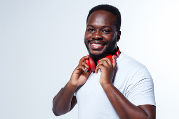 A smart actor is looking at us and smiling while holding cool red headphones.