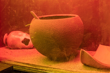 Old crockery made of clay with red illumination behind antique glass
