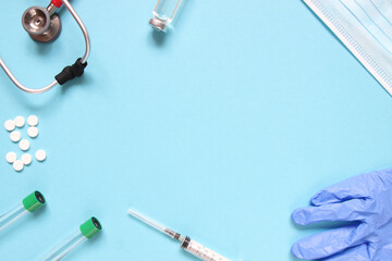 Top view of red stetoscope, syringe, mask, ampoules and white pills on blue background. Medicine concept.