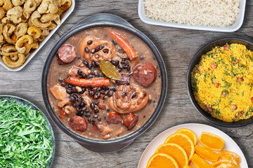 Traditional Brazilian feijoada, with typical side dishes, pork rinds, cabbage, orange, rice and farofa (manioc flour).