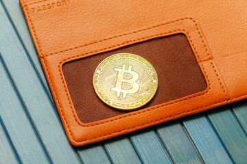 One single gold bitcoin coin symbol laying on an orange wallet, object closeup, detail, nobody. Crypto currencies storing, cryptocurrency wallets, digital currency storage abstract concept, nobody