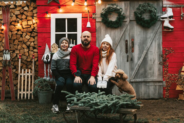 Family father and his children in Santa hats a boy and a girl with their dog sit on the porch of a house decorated for Christmas, the concept of a family holiday of Christmas and New year