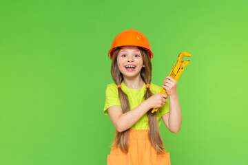 Children is holding a wrench. Construction and repair. A little girl is holding an adjustable tool in her hands.