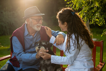 Nurse in white coat sitting on bench with senior man