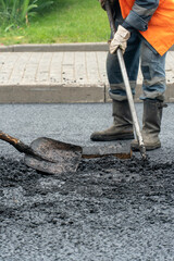 road repairs in the city. Filling holes and potholes on roads with fresh asphalt. Builders in boots...
