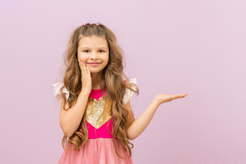 The little princess points to the advertisement.  A child with curly hair. Purple isolated background.