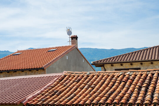 Tiled roofs with a chimney on one of the roofs are depicted against a blue sky. The theme is the traditional architecture of  Spain, Europe.