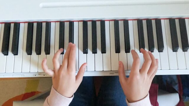 Closeup of child hands learning playing by electric piano.