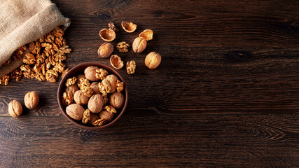 Fototapeta na wymiar Walnut kernels and whole walnuts on rustic old wooden table