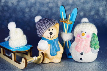 Figures of a snowman and a cat in a knitted hat with skis and sleds. Macro image of cute New Year...