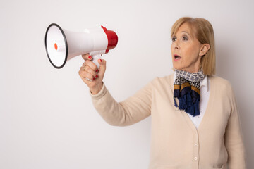portrait of a happy senior woman shouting with megaphone over white background