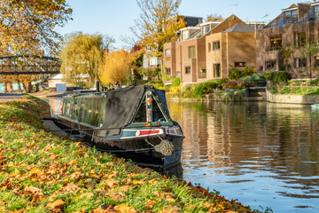 A traditional narrow house boat moored on the River Cam in Jesus Green on a bright autumn day