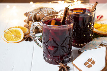warm mulled wine with spices and cinnamon sticks, gingerbread cookies and oranges