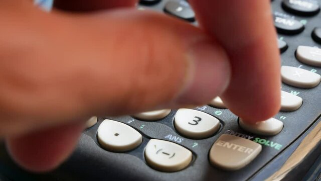 Anonymous man using a modern scientific calculator, hand detail, object closeup. Math university course education, advanced mathematics and physics research, business accounting abstract concept