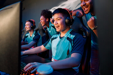 Team of excited cybersports gamers looking at PC screen and celebrating success while participating in esports tournament in gaming club © Yaroslav Astakhov