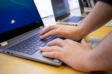 Manos de hombre en port&aacute;til de exposici&oacute;n en tienda electr&oacute;nica