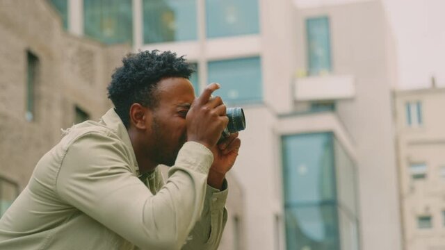 Young man in city taking photo on digital camera to post to social media - shot in slow motion