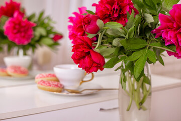Client place in hairdressing beauty salon with cup of tea, donuts and peonies flowers