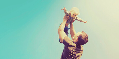 Happy father and son playing having fun together outdoors on blue sky background