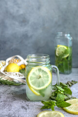 fresh lemonade on grey background, biologic lemons and mint. a glass of citrus lemonade