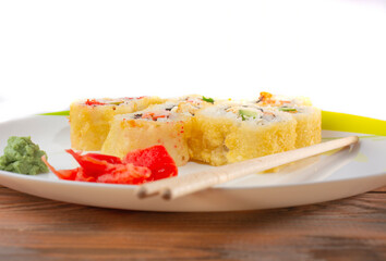 close-up of sushi on a white plate with wasabi and ginger and wooden chopsticks