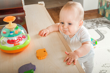 Baby plays on floor with educational toys, rattles and teething toys. Crawling babies at 8 months..