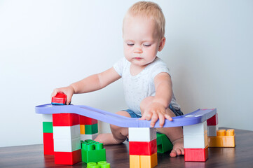 Toddler boy plays with constructor, cars, blocks close-up. Educational toys for preschool children...