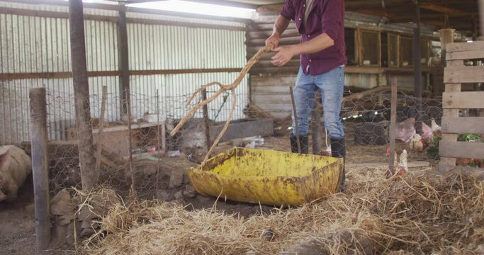 Caucasian man working on farm, cleaning pigsty